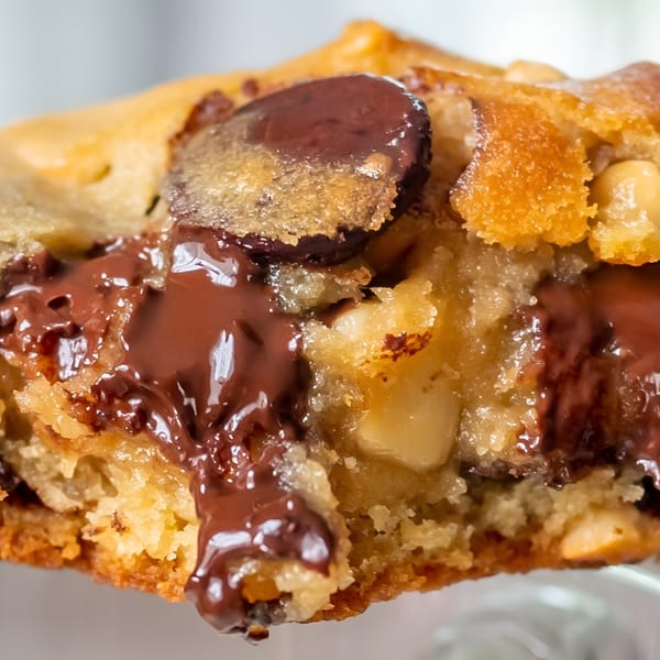 Close-up of a warm chocolate chip cookie, with melted chocolate oozing from the center.