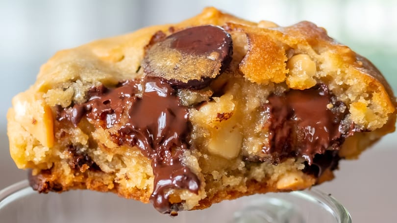Close-up of a warm chocolate chip cookie, with melted chocolate oozing from the center.