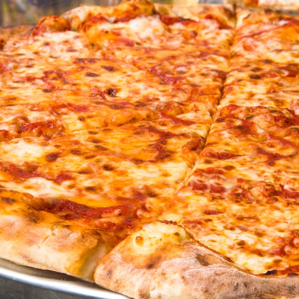 Close-up of a large, freshly baked cheese pizza with a golden crust, sliced and ready to serve.